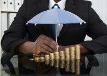 Man with mini umbrella covering coins - Equity-Indexed Annuities - Donner's Financial Services